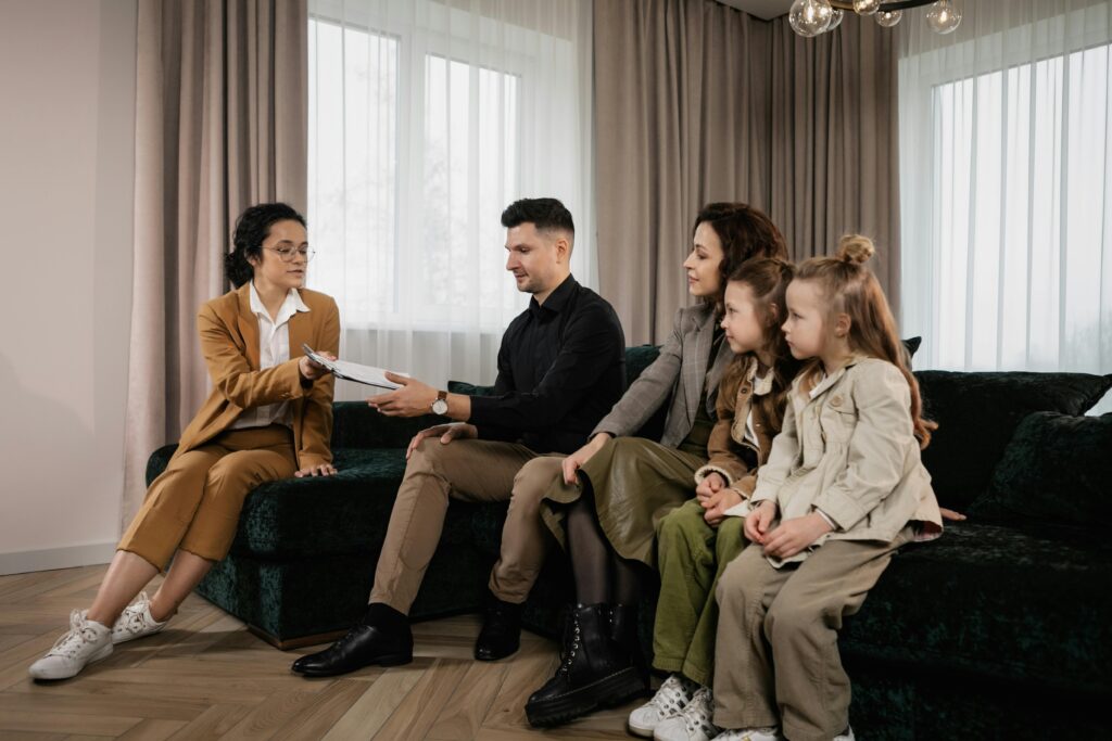 A family meets with a real estate agent in a stylish living room, reviewing documents for a potential home purchase.